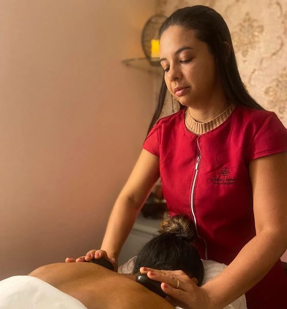 Massoterapeuta Liane Vieira aplicando a técnica de massagem com pedras quentes em seu consultório em Brasília para alívio de dores.