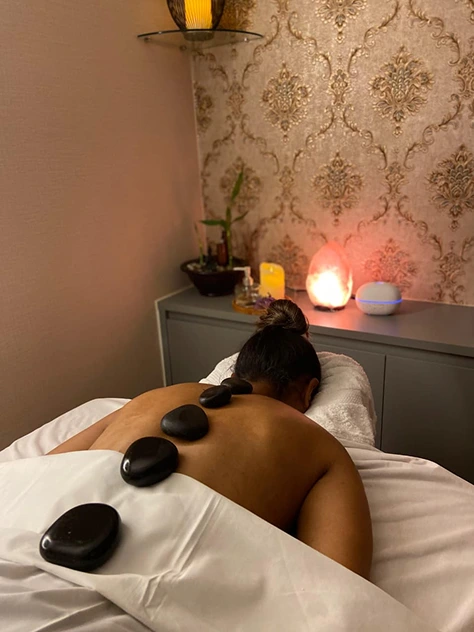 Terapia relaxante com pedras quentes sendo aplicada pela massoterapeuta Liane Vieira em seu espaço.