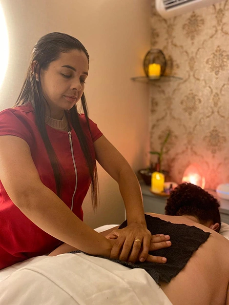 Sessão de massagem terapêutica com toalhas aquecidas para alívio de dores musculares no espaço de Liane Vieira em Brasília.
